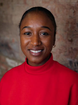 A woman in a red jumper with her hair up, smilng