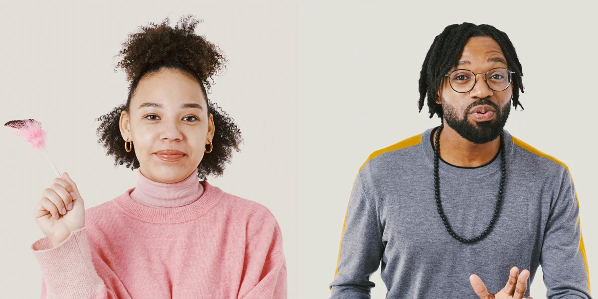 A woman with tight curls holding a pink feather and wearing a pink jumper; A man with short dreadlocks and glasses wearing a grey and orange jumper