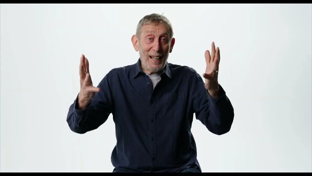 Michael Rosen smiling with hands raised