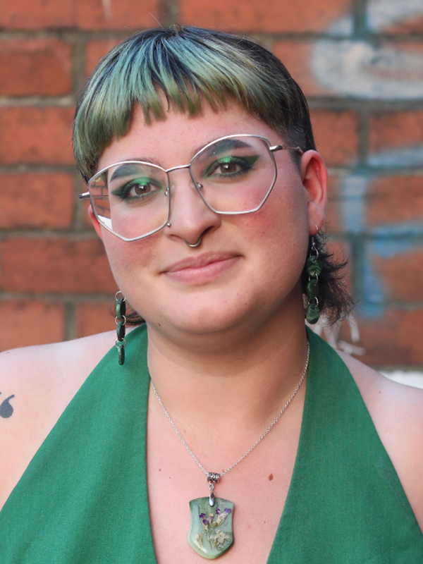 Amy with short blue mullet, green halter neck and large glasses